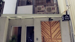 Un edificio de varios pisos con una puerta de madera grande, una planta en maceta y un letrero que indica un hotel fond.'