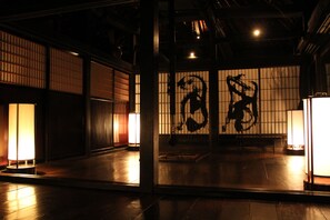 A traditional Japanese room with tatami flooring, sliding doors, and a shoji screen with calligraphy.