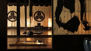Ein traditioneller japanischer Raum mit Tatami-Bodenbelag, Shoji-Schirm und einem großen Schwarz-Weiß-Gemälde an der Wand.
