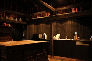 Uma cozinha com pouca luz, armários e bancada de madeira e um micro-ondas.