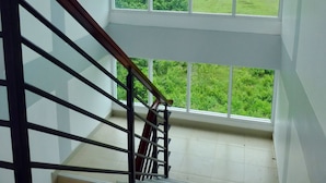 Una escalera conduce a un rellano con un gran ventanal que ofrece vistas de un paisaje verde.