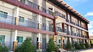 Un edificio de varios pisos con balcones, planta baja de concreto y cielo despejado.