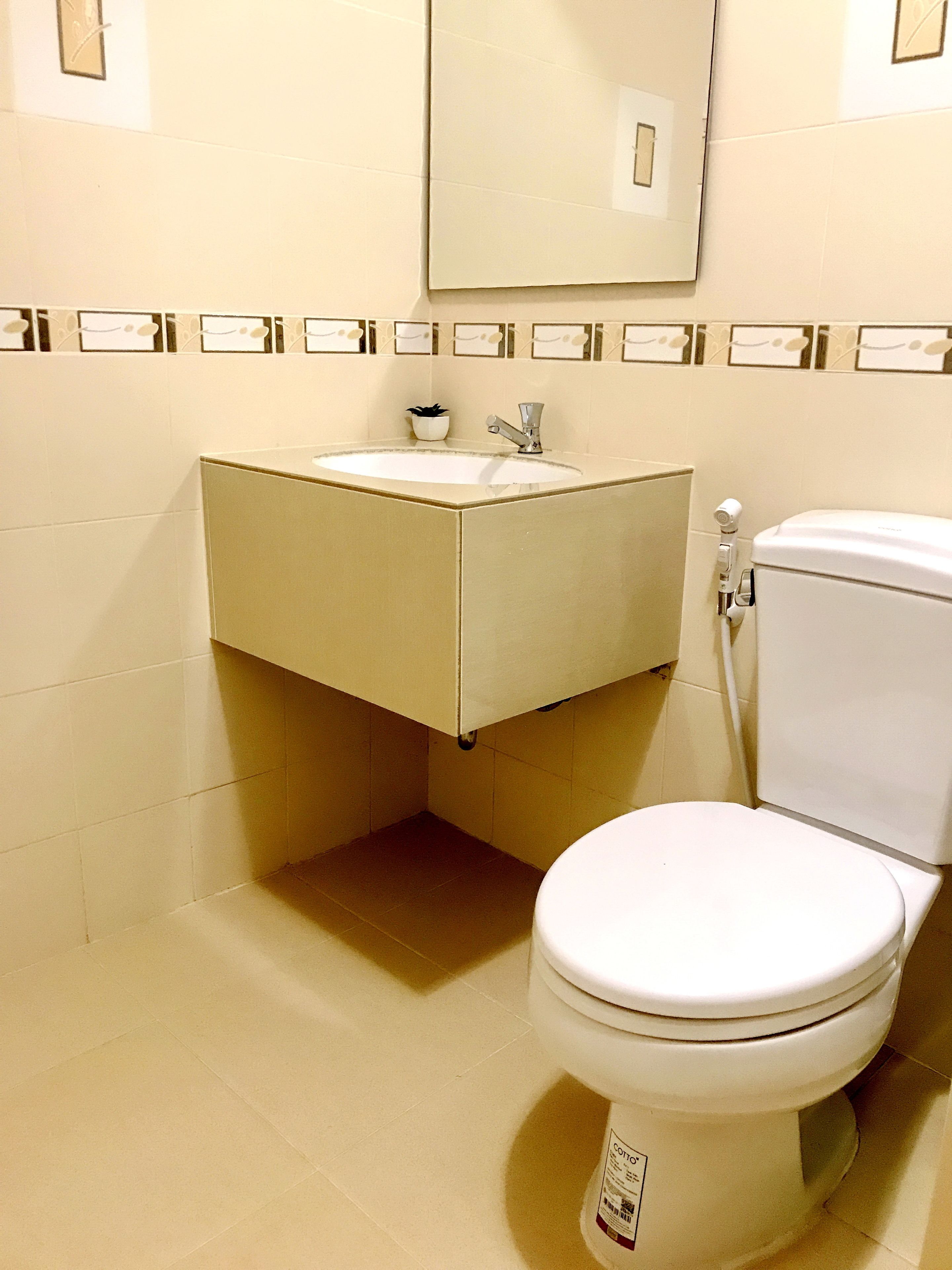 A bathroom with a toilet, a sink, and a mirror.