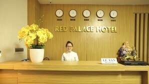 A reception desk at the Red Palace Hotel with clocks indicating different time zones, a receptionist, and a statue. - Red Palace Hotel (Da Nang)