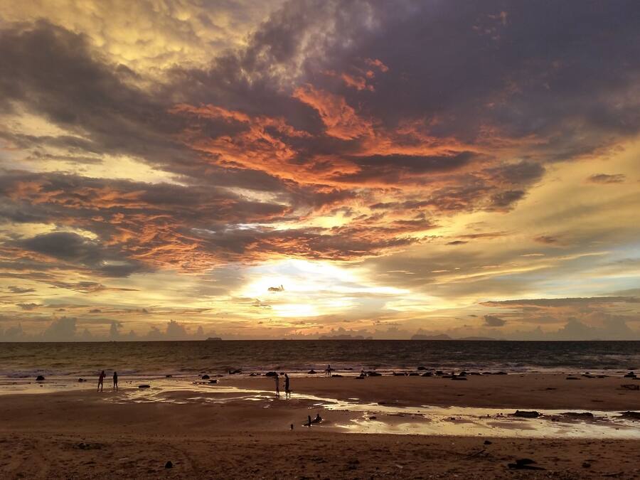 A beach with people and scattered rocks.