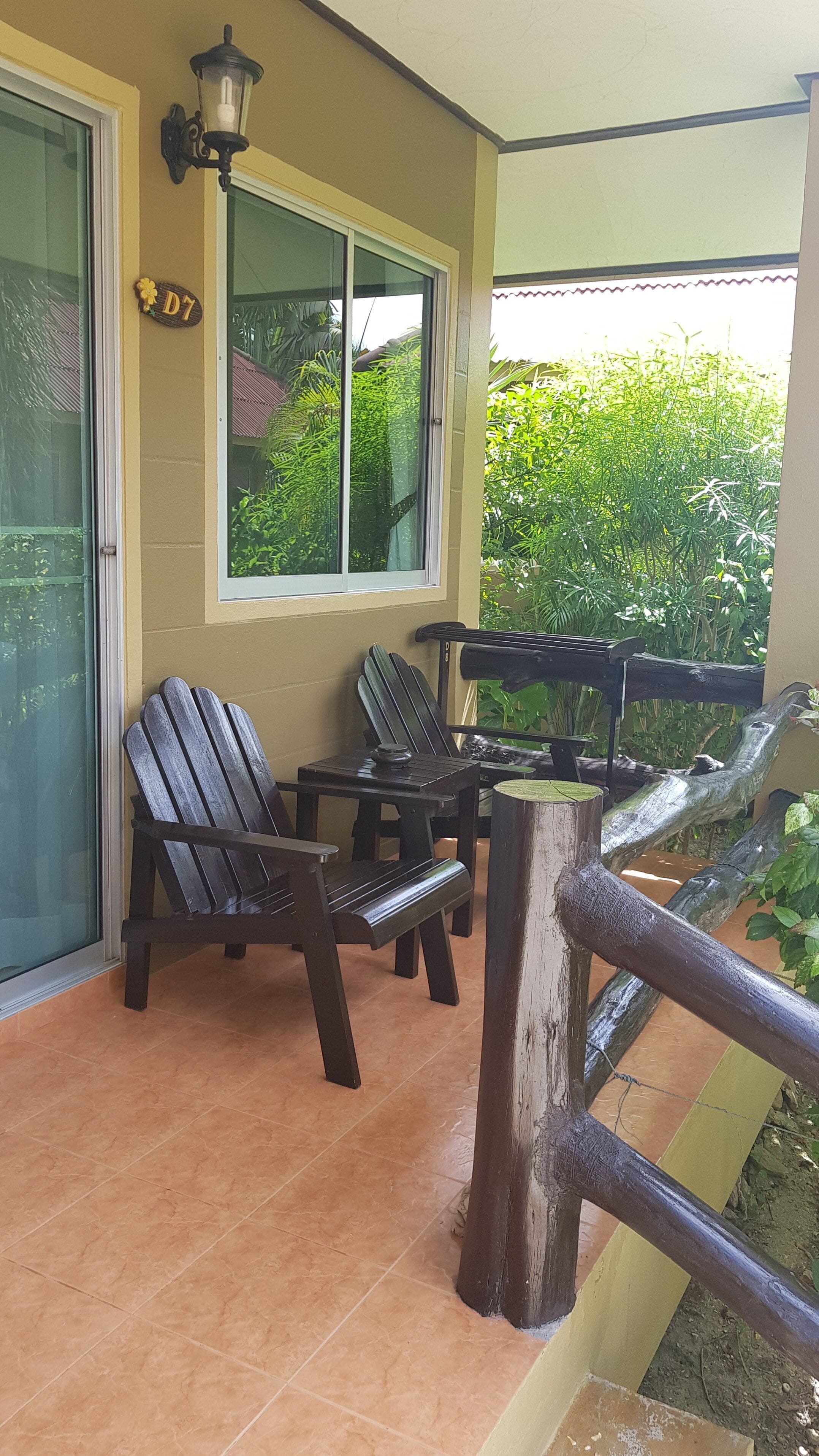 Un espacio de estar al aire libre techado con dos sillas Adirondack, una mesa de madera y un farol.