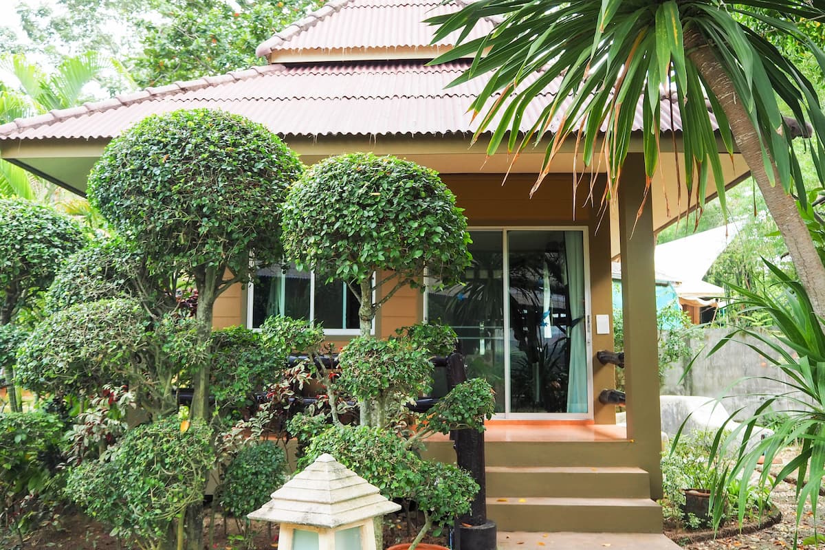 A traditional house with a tiled roof, surrounded by lush greenery and well-maintained plants.