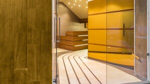 Un interior moderno con suelo de madera, un banco curvo y una partición de vidrio con paneles amarillos.