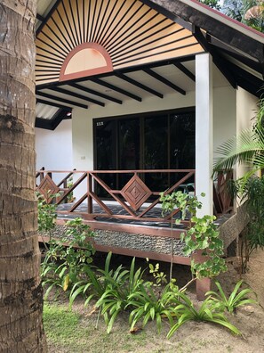 A covered outdoor area with a wooden ceiling, a stone floor, and a metal railing. - Noble House Beach Resort (Ko Lanta)