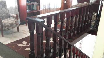 A wooden staircase with a patterned carpet and a chair in a room with a bookshelf.