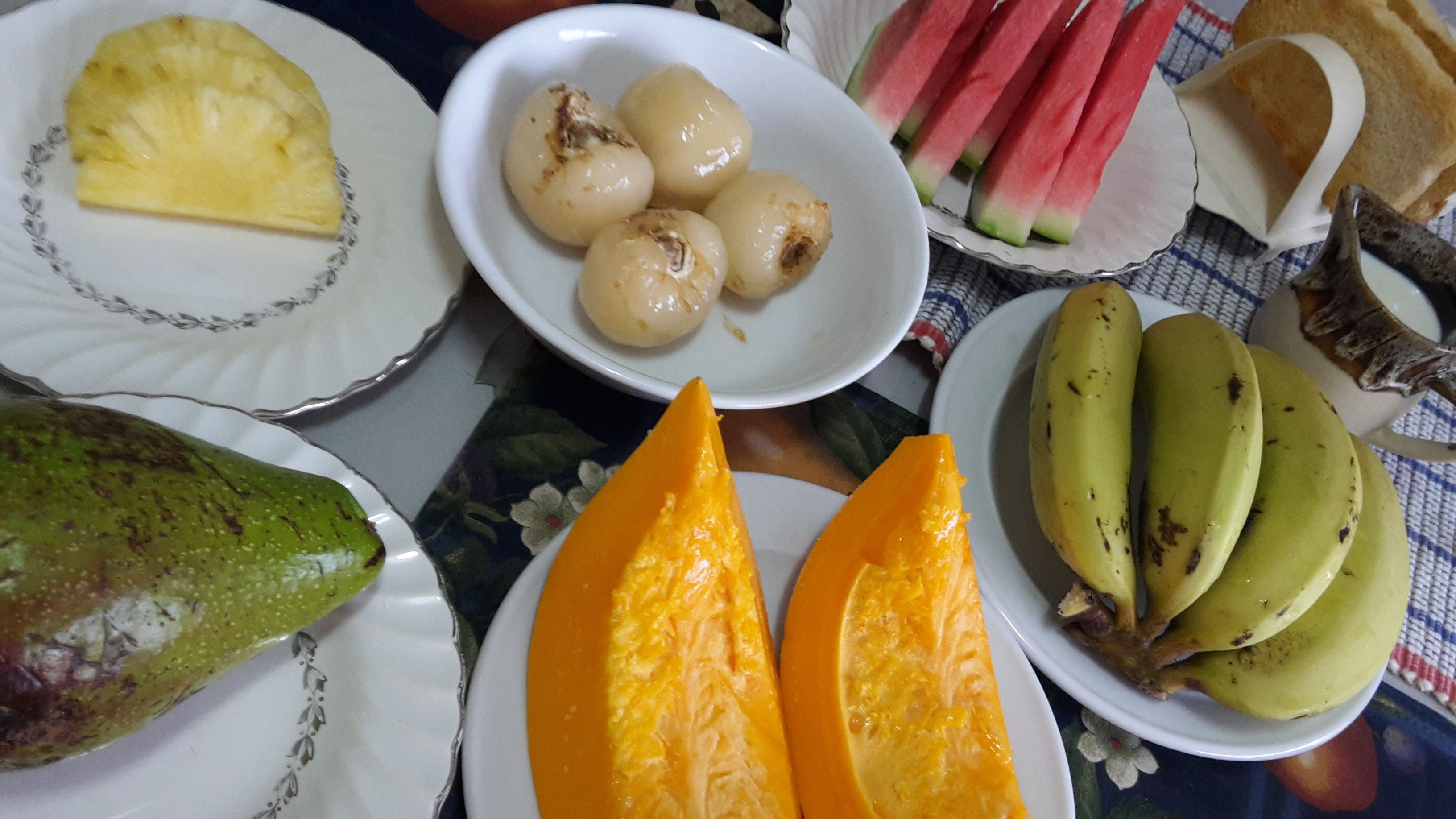 Une table avec différents fruits et une assiette de pain.