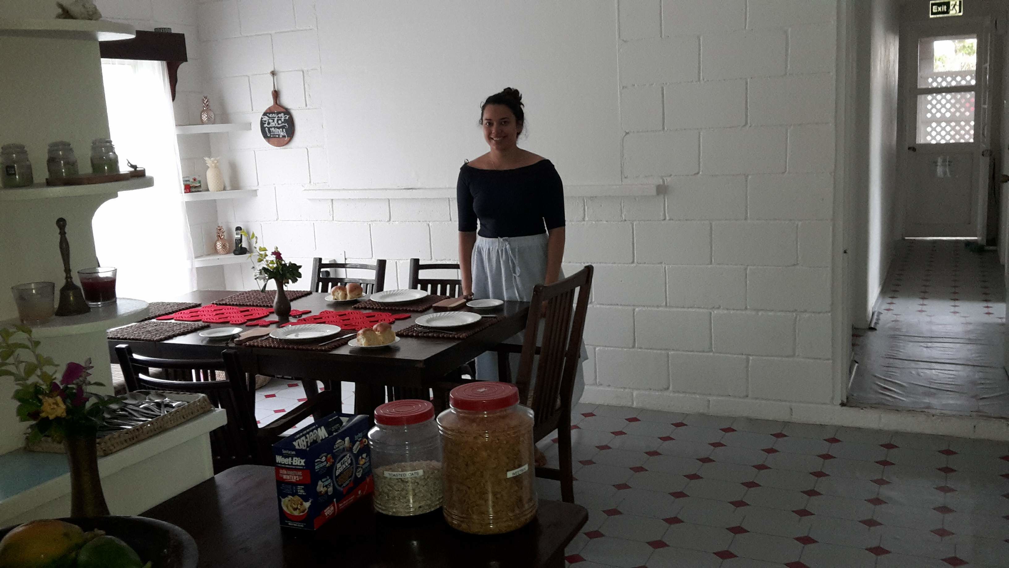 A dining area with a table set for two, a box of Weet-Bix, and two jars of oats.