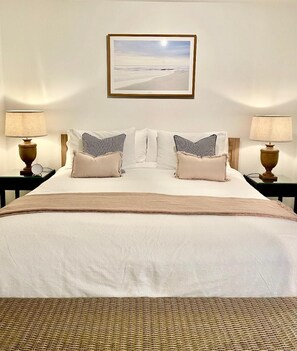 A neatly made bed with a white and beige color scheme, flanked by two bedside tables with lamps and a framed picture above. - Edge17 Port Fairy Wharf (Port Fairy)
