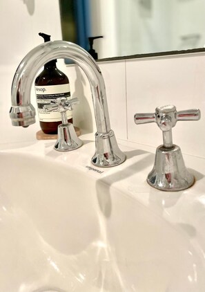A bathroom sink with a chrome faucet and a bottle of hand soap. - Edge17 Port Fairy Wharf (Port Fairy)