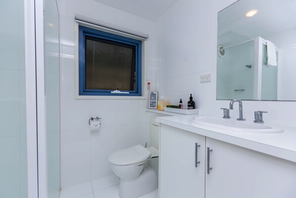 Un baño moderno con inodoro, lavamanos y ducha.