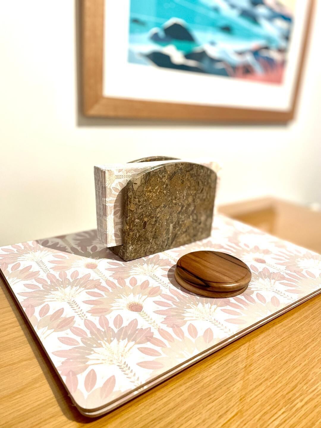 A wooden block on a patterned surface with a framed picture in the background.
