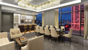A modern dining area with a chandelier, a bar, and a view of the cityscape at night. - The Granite Luxury Hotel Penang (George Town)