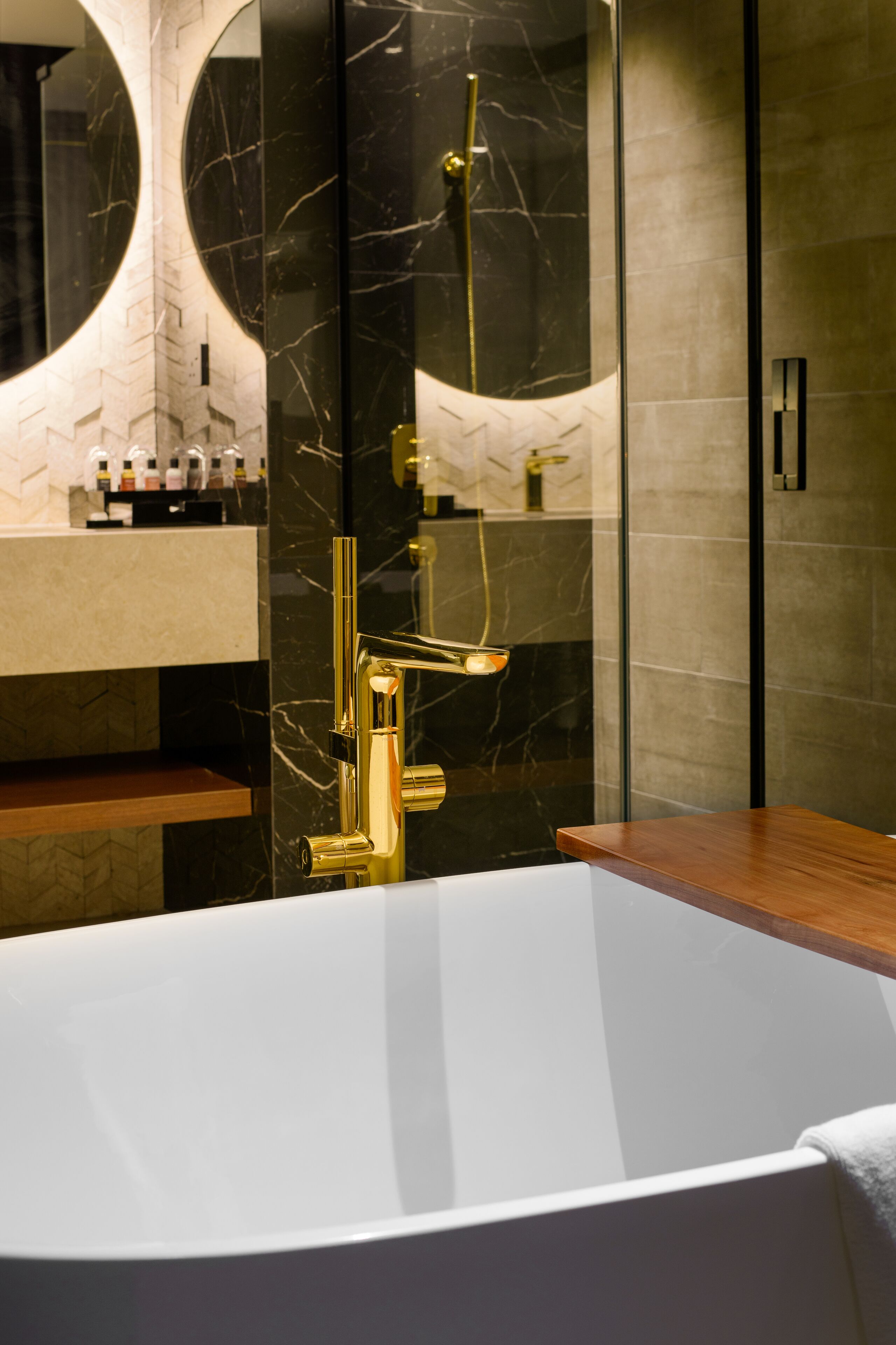 A modern bathroom with a freestanding bathtub, a gold faucet, and a glass-enclosed shower area.