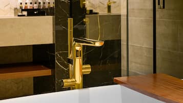 A modern bathroom with a freestanding bathtub, a gold faucet, and a glass-enclosed shower area.
