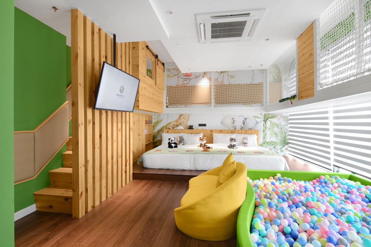 A child-friendly room with a wooden staircase, a bed with a panda and animal-themed decor, a green bean bag chair, and a colorful ball pit.