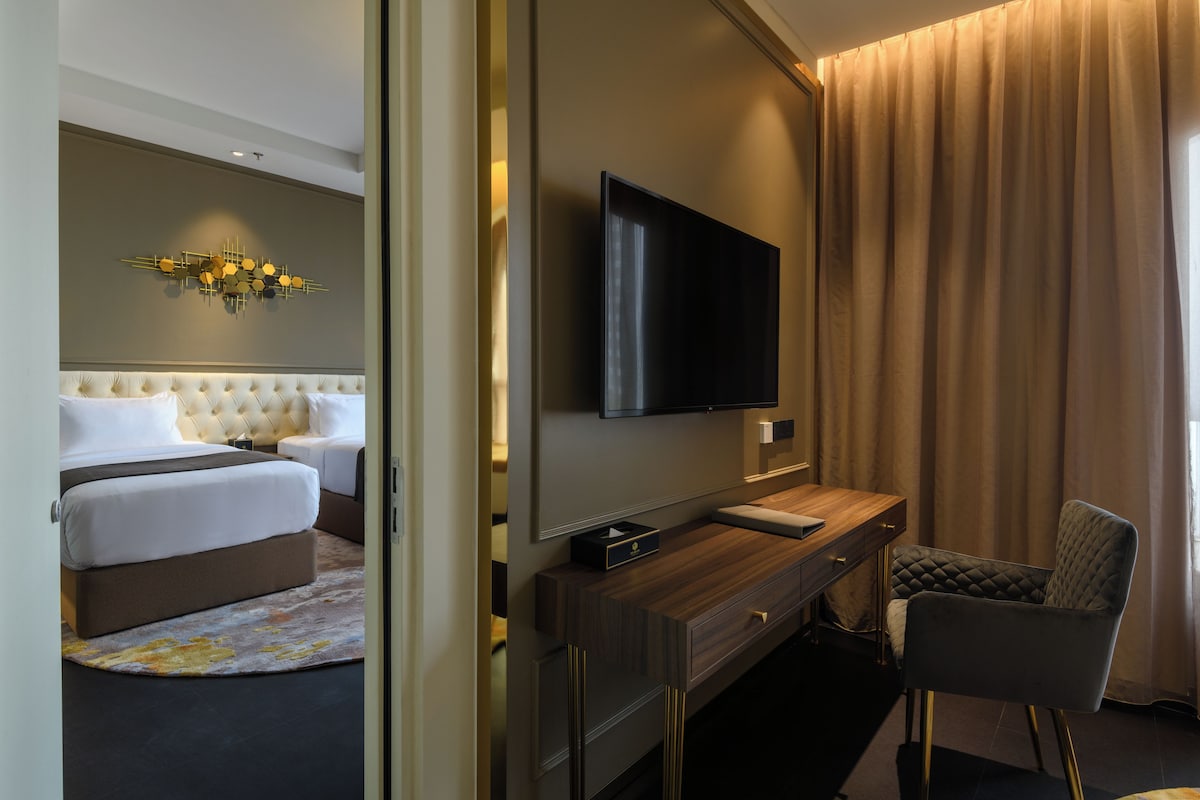 A hotel room with a bed, a TV, a desk, and a chair.