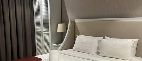 A hotel room with a large bed, a bedside table, a lamp, and a wardrobe.