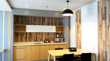 A modern kitchen with wooden cabinets, a wooden countertop, a sink, a kettle, a toaster, and a dining table with chairs.