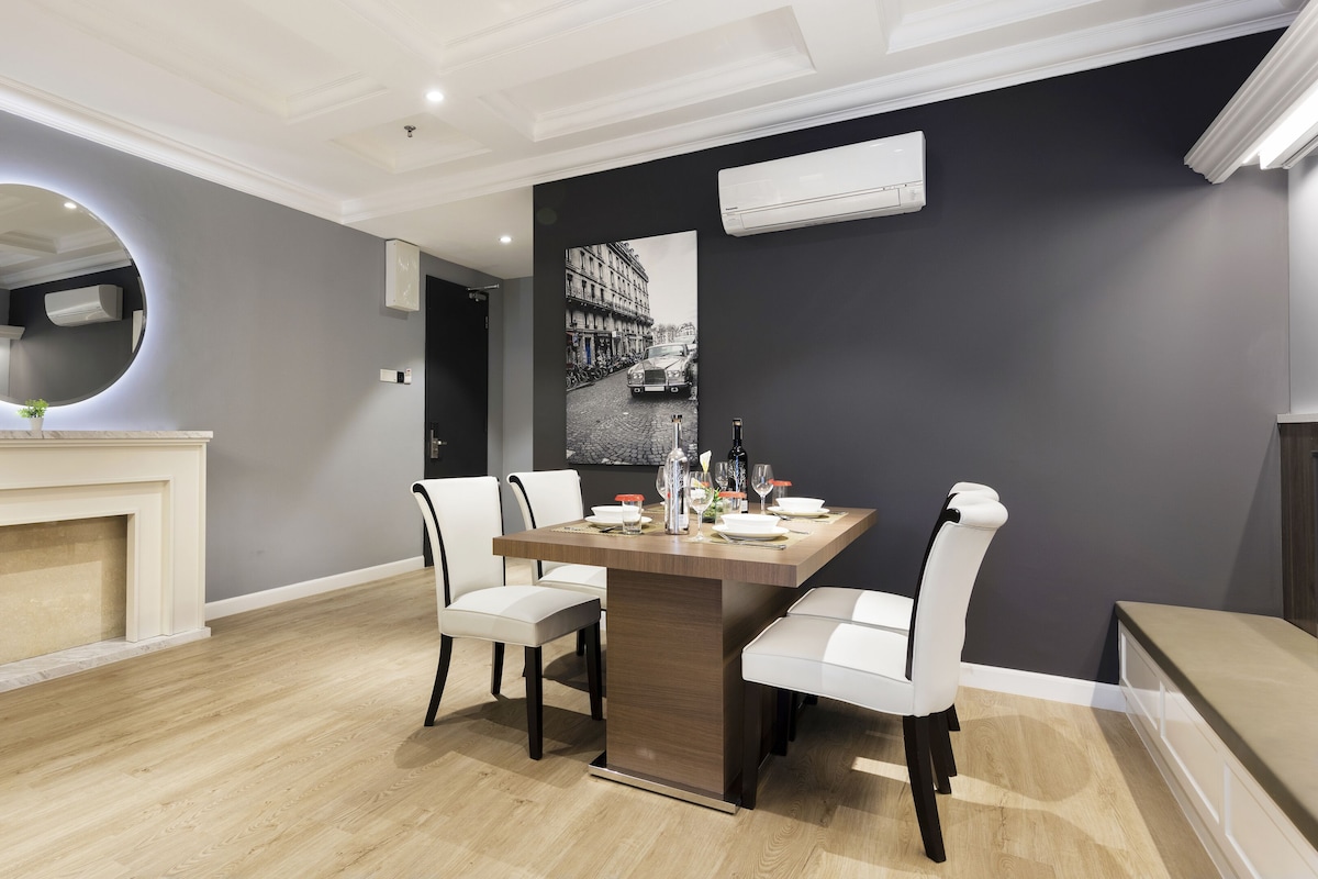 A dining area with a round mirror, a fireplace, and a table set for four.