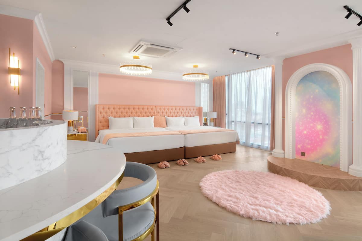 A modern bedroom with a large bed, a marble vanity, and a pink fluffy rug.