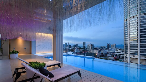 A modern outdoor lounge area with a pool, overlooking a cityscape. - The Granite Luxury Hotel Penang (George Town)