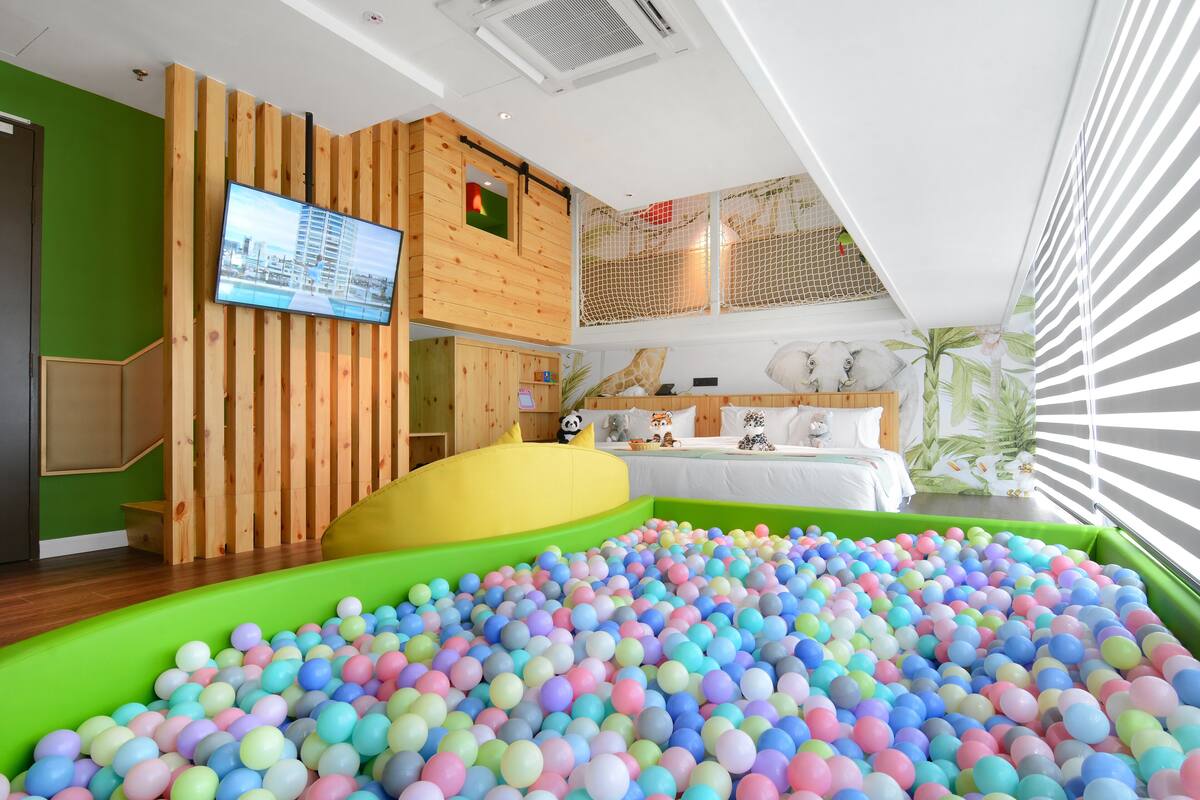 A children's play area with a ball pit and a TV mounted on a wooden wall.