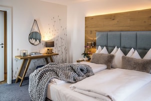 Habitación de hotel con cama, mesita de noche, lámpara y un espejo montado en la pared.