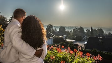 A couple embracing, overlooking a residential area with houses and a clear sky.