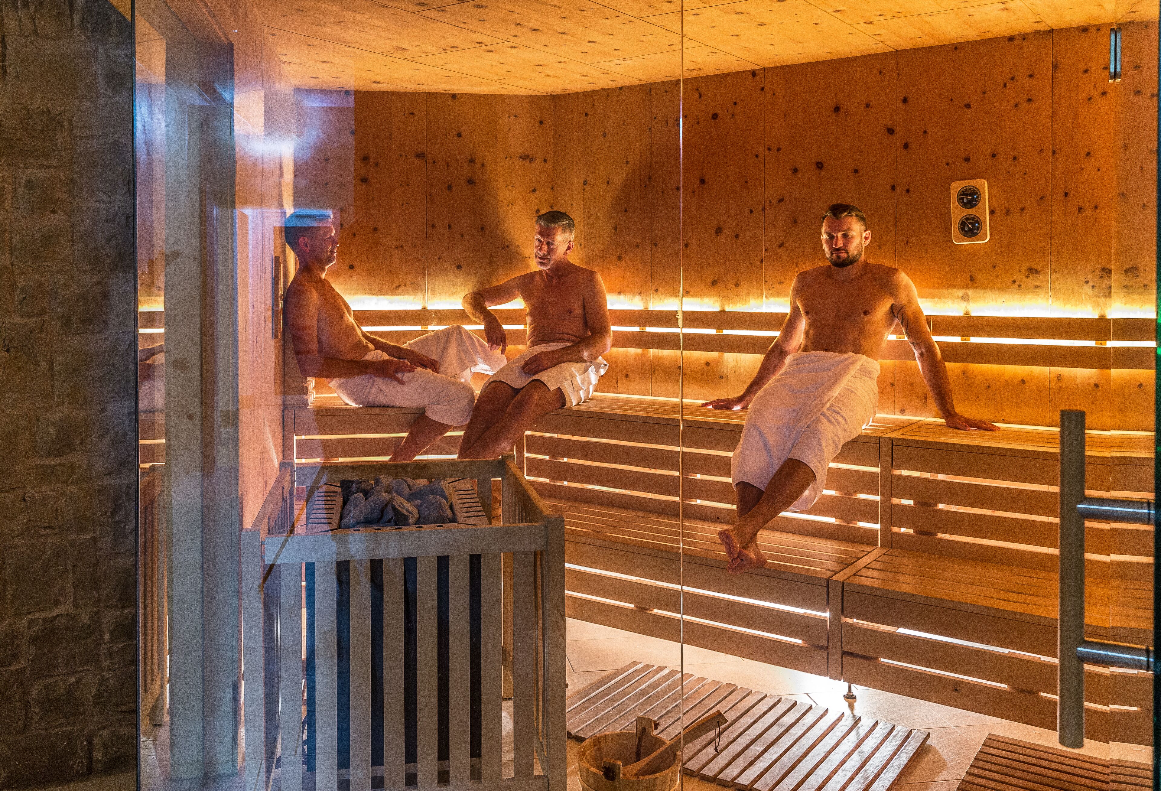 Een sauna met houten banken en een glazen scheiding.