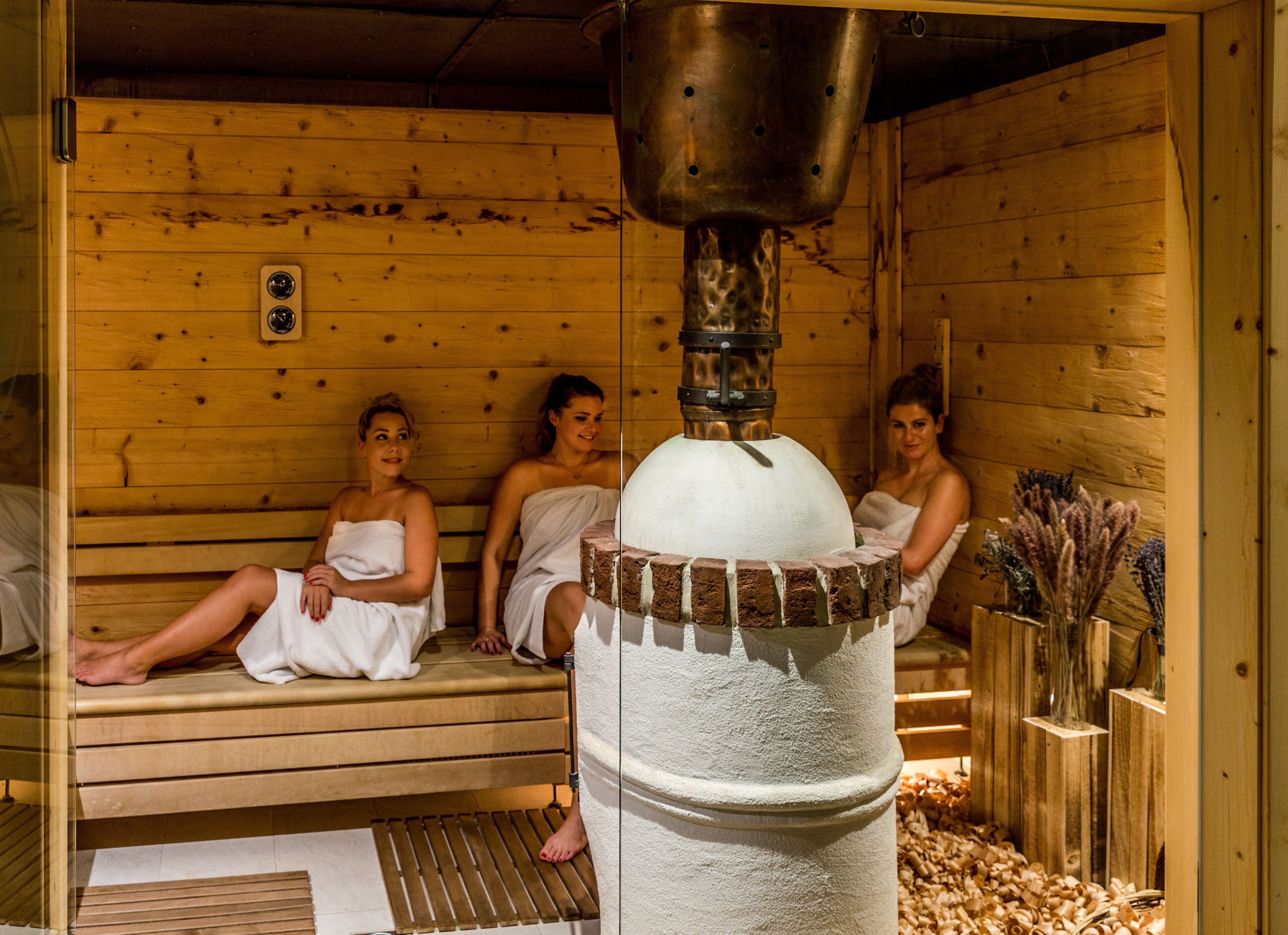 Un sauna avec des bancs en bois et un générateur de vapeur central.