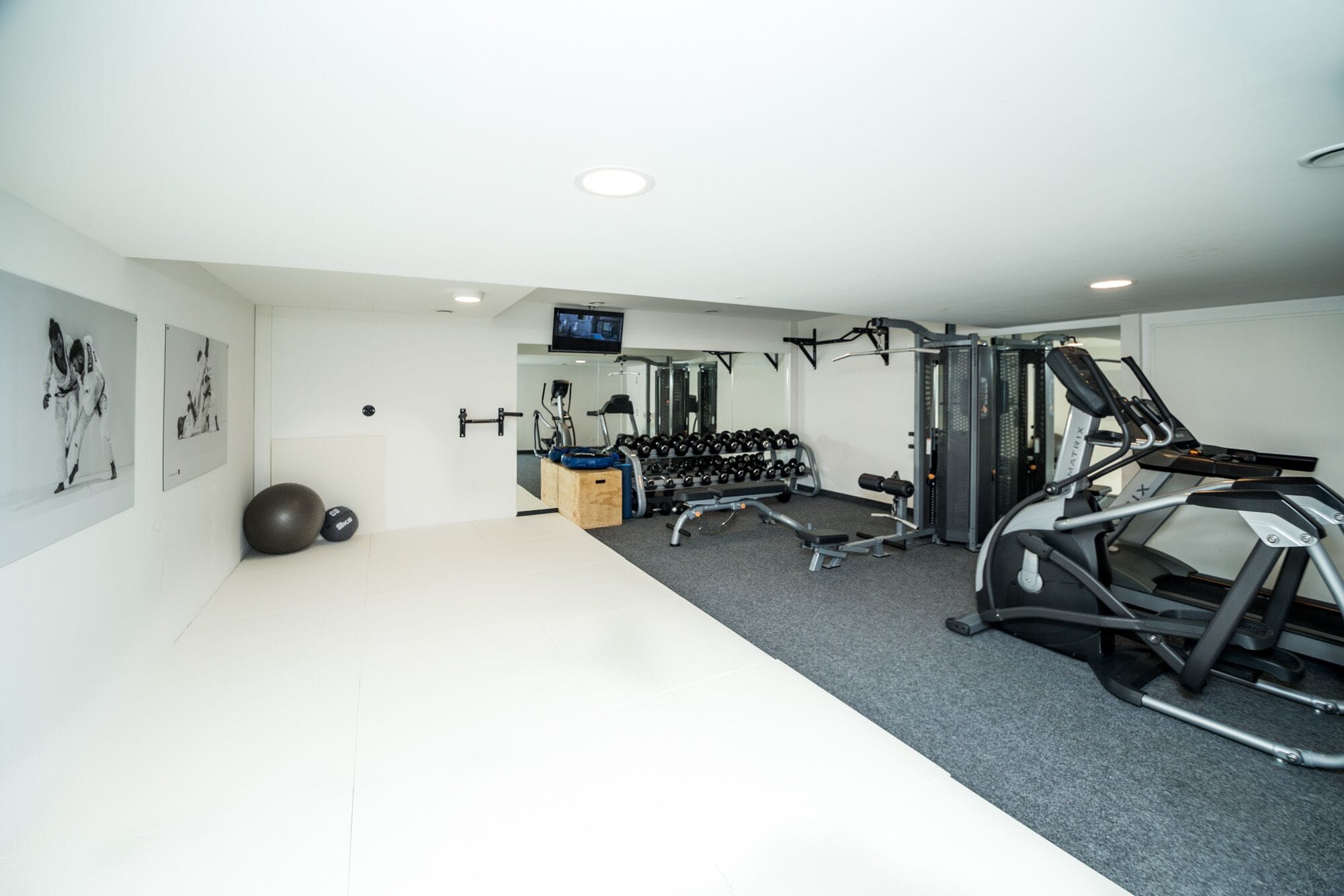 Une salle de sport moderne équipée de machines de cardio, de poids et d’un écran de télévision.