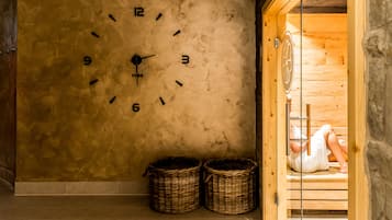 Eine Wanduhr mit Ziffern und Zeigern, zwei Korbwäsche und eine Holztür zur Sauna.