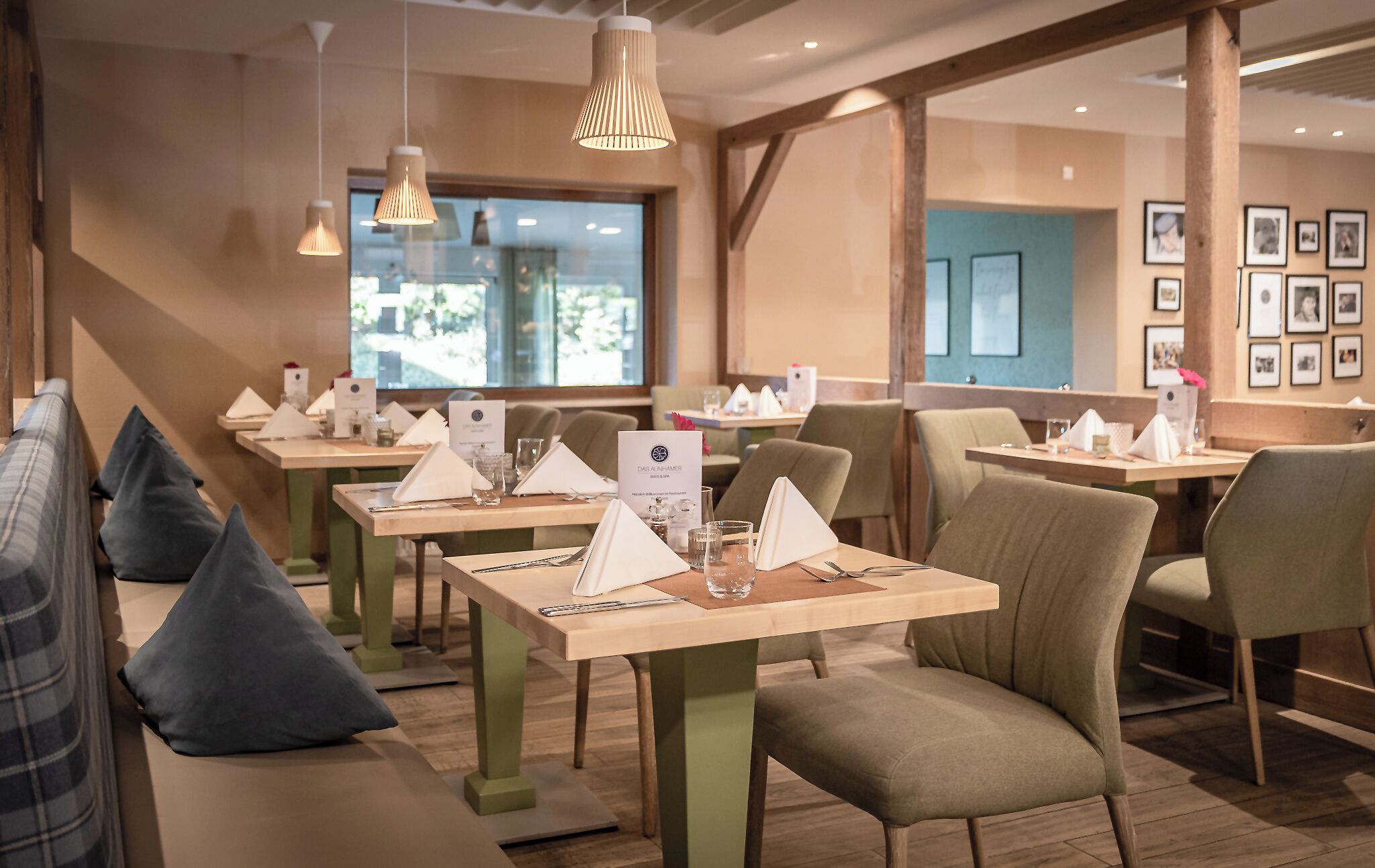 A restaurant with multiple tables, each set with a menu, glasses, and cutlery.