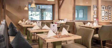 A restaurant with multiple tables, each set with a menu, glasses, and cutlery.