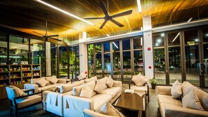 A modern lounge area with sofas, armchairs, and a coffee table. - Burgundy Residence (Si Maha Phot)