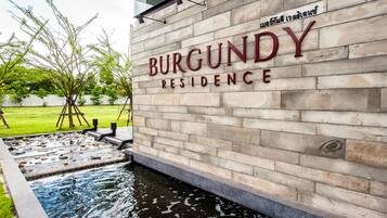 Kivimuuri, jossa on teksti ”BURGUNDY RESIDENCE”, ja sen edessä pieni vesiaihe.