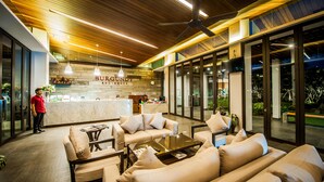 A modern lobby with a reception desk, sofas, and a coffee table. - Burgundy Residence (Si Maha Phot)
