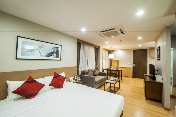 Una habitación de hotel con cama, sofá, escritorio y zona de comedor.