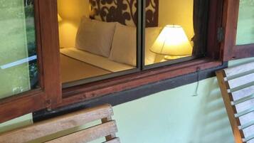 Una habitación con una cama, una mesita de noche y una ventana que ofrece vistas al exterior.