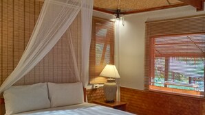 A bed with a canopy, wooden headboard, bedside lamp, and wooden floor. - Mookies Bungalow (Ko Mook)