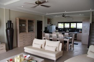 Una sala de estar moderna con sofá, mesa de comedor y zona de cocina.