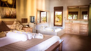 A bedroom with a large bed, a bathroom with a bathtub, and a view of the outdoors. - The Beach Front Villas - North Bali (Sawan)