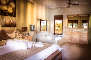 Un dormitorio con una cama grande, un baño con bañera y vistas al exterior.