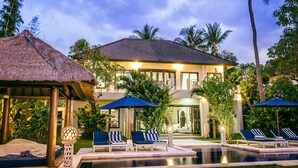 A resort with a pool, lounge chairs, and umbrellas. - The Beach Front Villas - North Bali (Sawan)