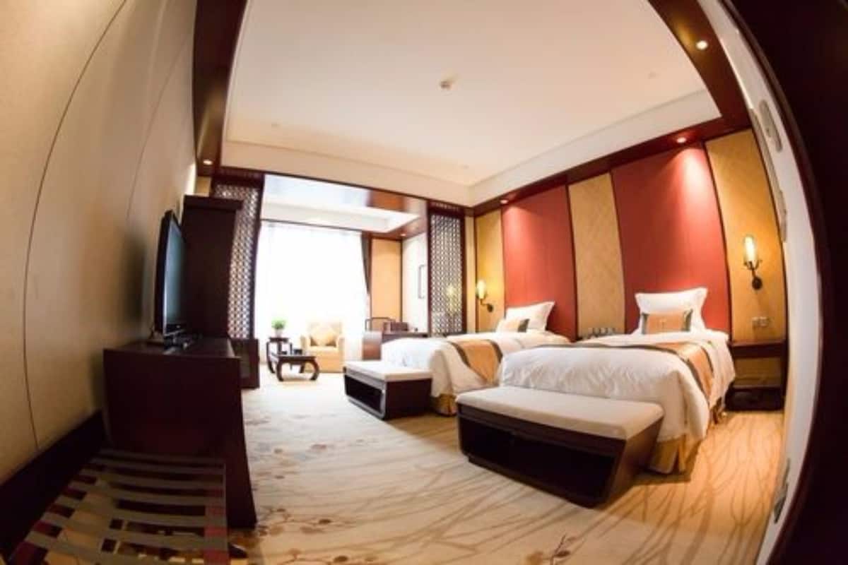 A hotel room with a large bed, a desk, a TV, and a view of the outdoors.